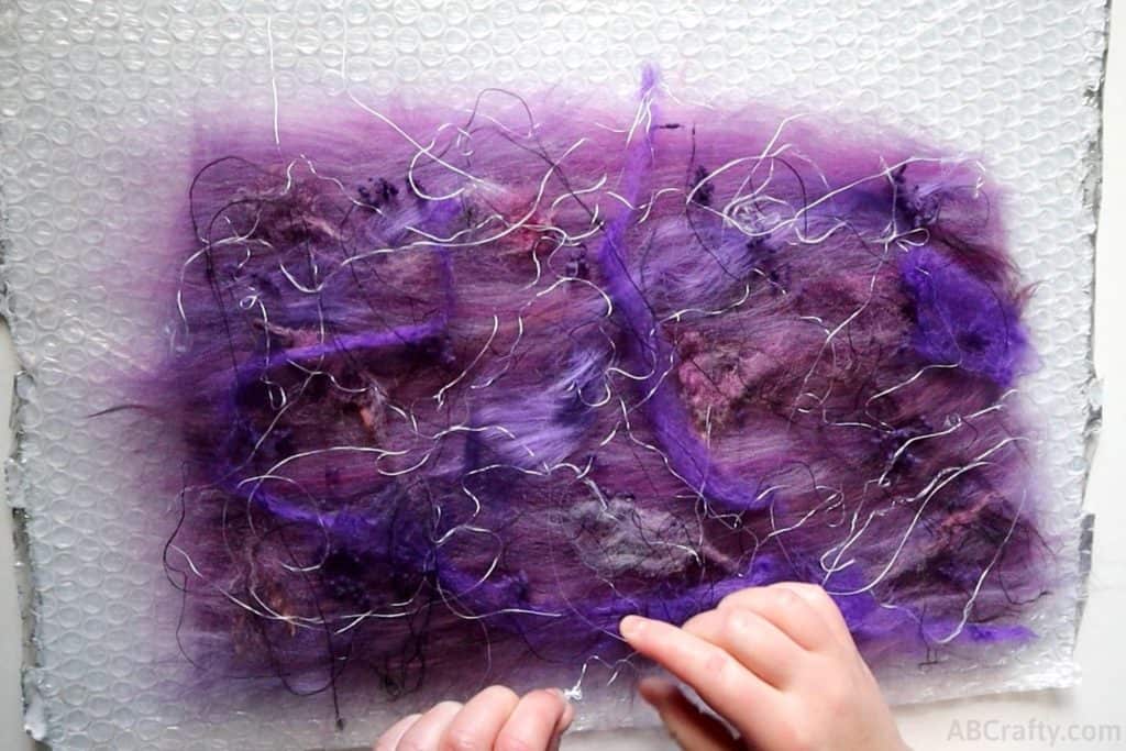 adding viscose, silk, and other felting embellishments to purple wool