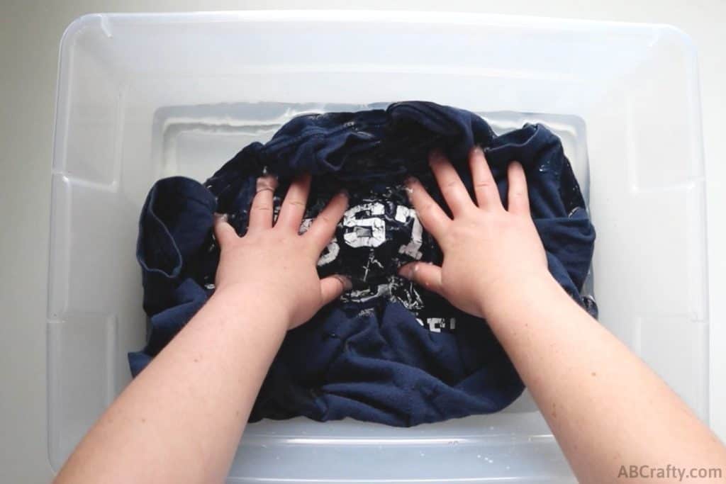 dunking a blue Boston shirt into a tub of water