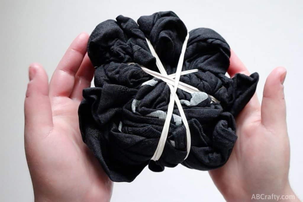 black t shirt bundled up and wrapped diagonally with rubber bands