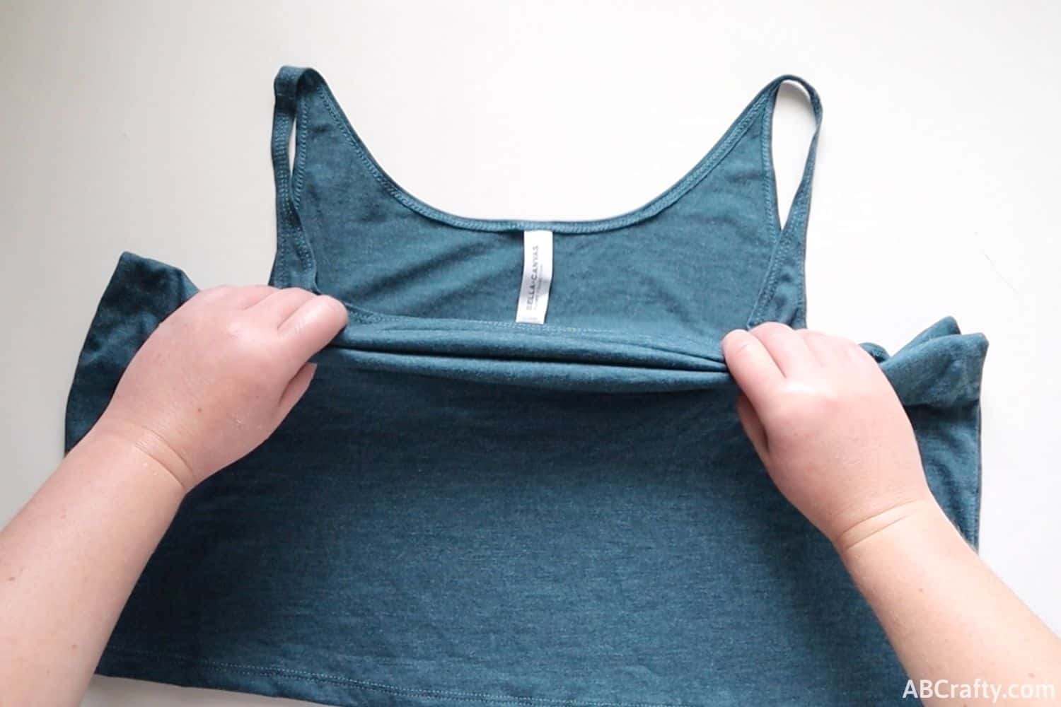 folding a blue tank top accordion style from the middle