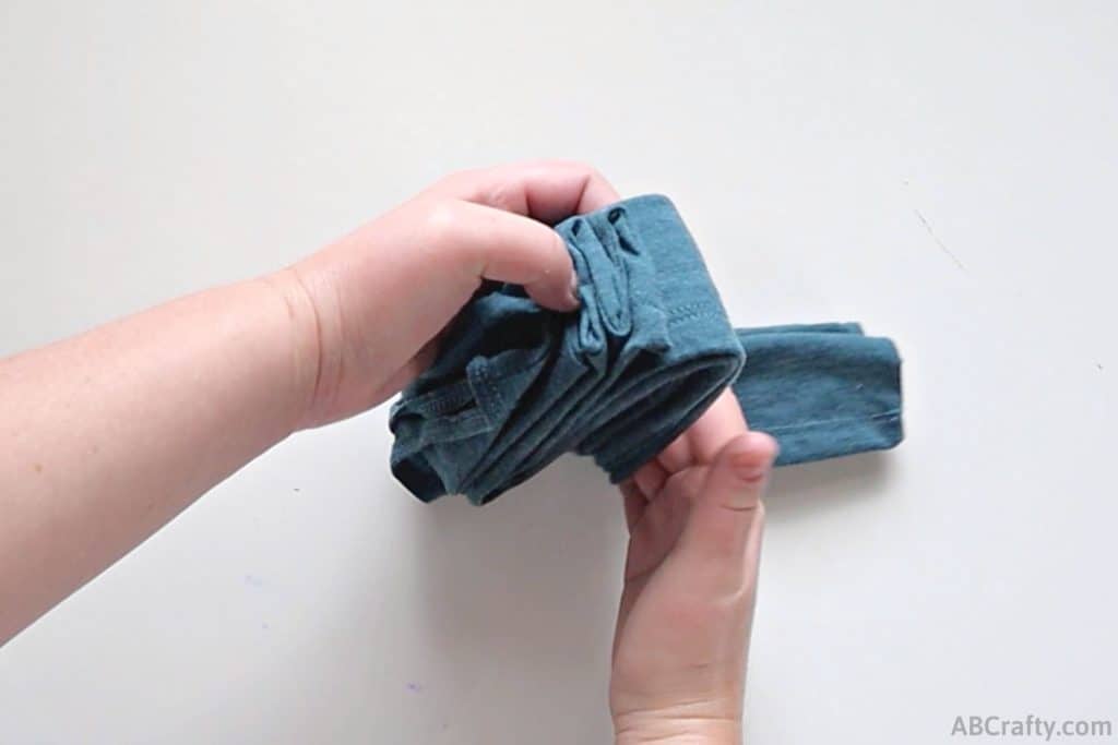 folding a folded blue tank top into thirds