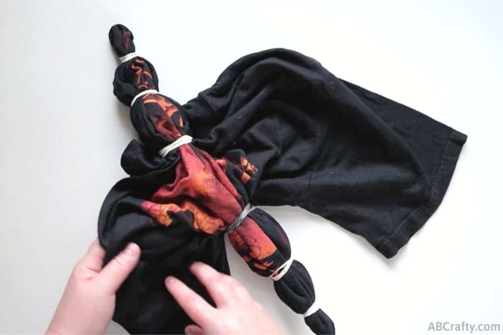 a black shirt with red and orange print wrapped on two sides with 3 rubber bands