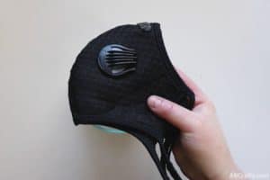 holding a black reusable dust mask