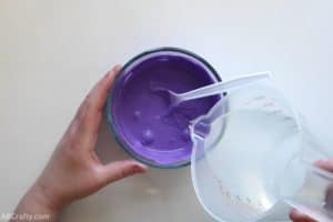 pouring clear liquid into a bowl of purple liquid