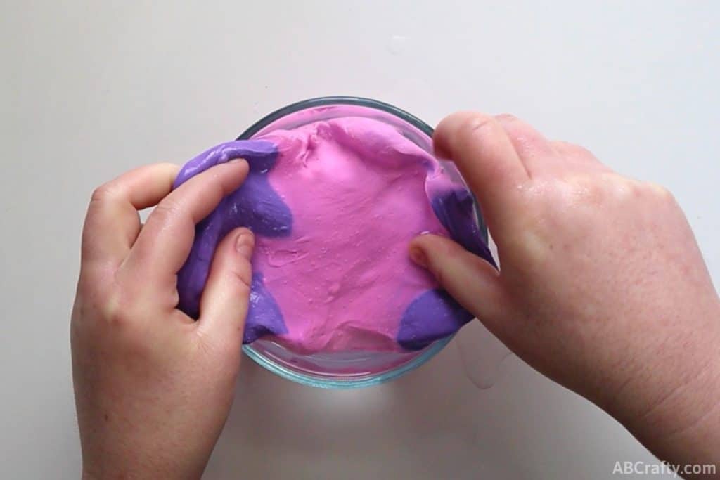 putting purple color changing slime into a bowl of water so it changes colors to pink