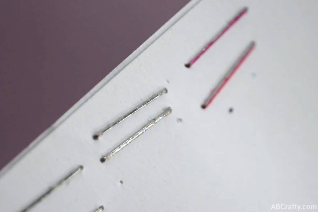 two glitter staples stapled into a piece of paper next to pink colored staples