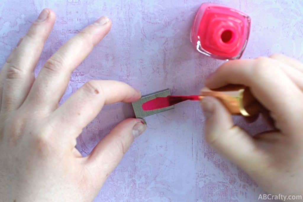 painting pink nail polish onto staples