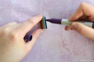 drawing a purple stripe onto staples with a sharpie to finish the rainbow on rainbow staples