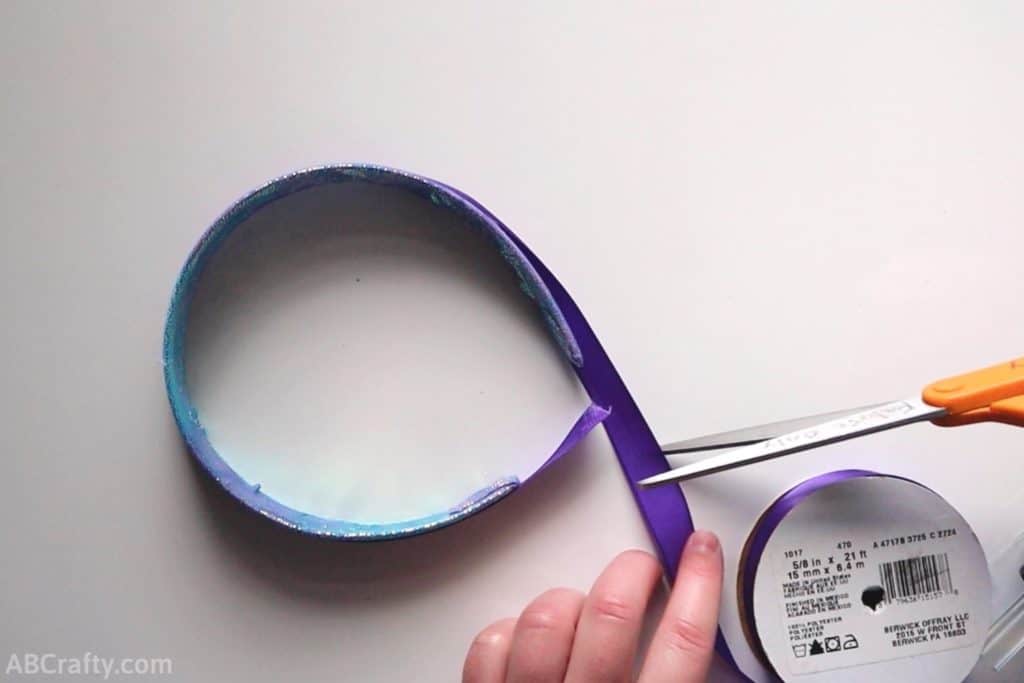 cutting purple satin ribbon around a headband