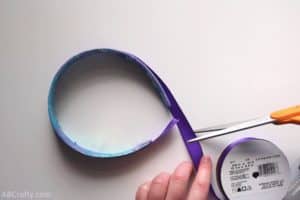 cutting purple satin ribbon around a headband