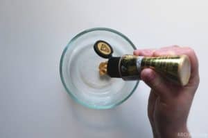 squeezing gold metallic paint into a bowl with clear liquid