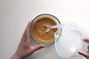 pouring liquid from a measuring cup into a bowl with gold liquid
