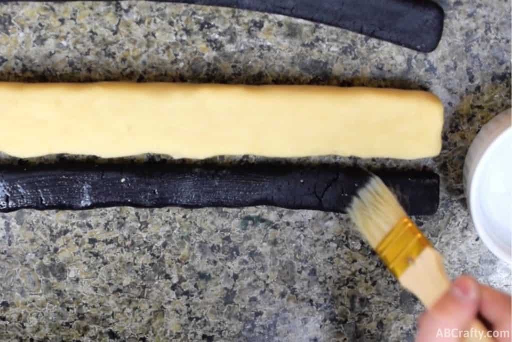 using pastry brush to brush black cookie dough with water
