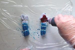 squeezing red dye onto the top of socks wrapped in rubber bands.