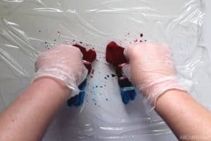 pushing on the red section of blue and red tie dye socks while wearing rubber gloves