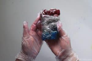 holding blue and red tie dye socks wrapped in plastic wrap