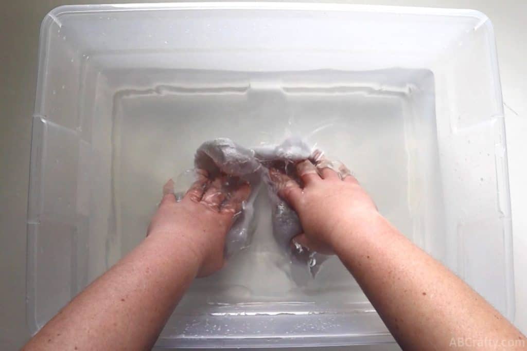 pushing white socks into a plastic bin with water
