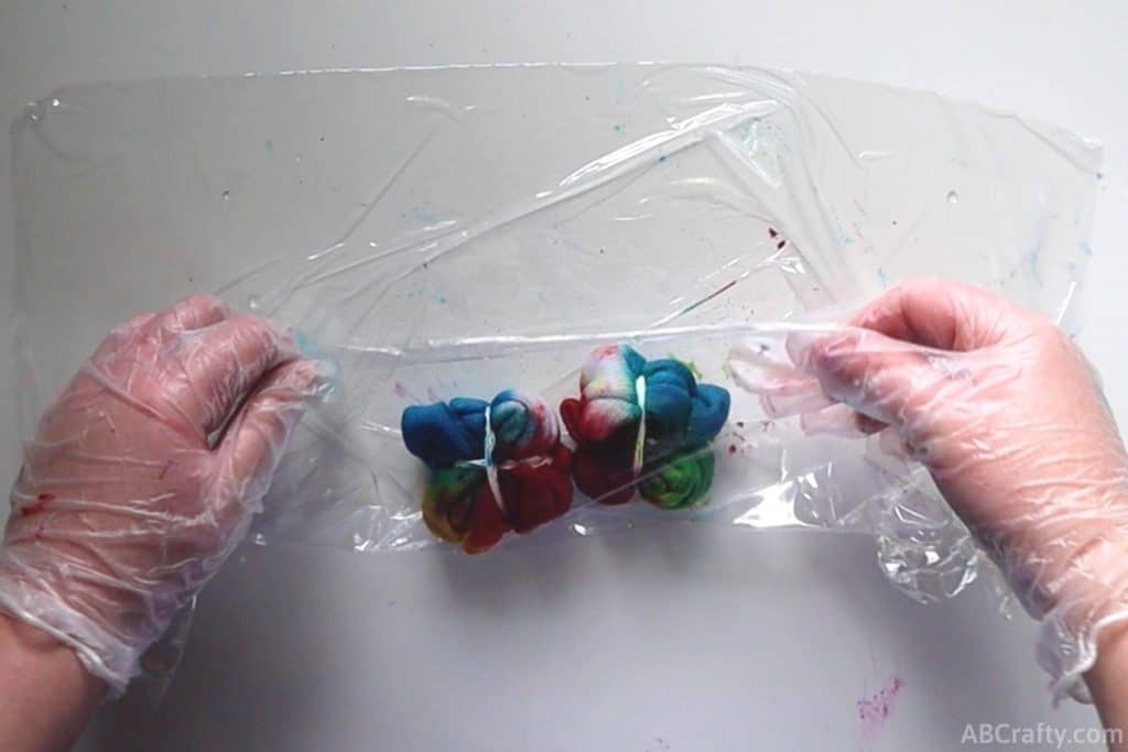 lifting plastic wrap over tie dye socks that have fresh dye on them