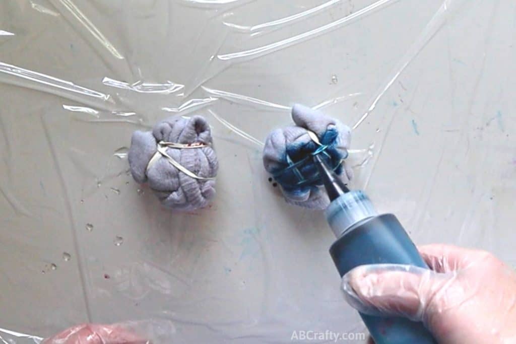adding blue dye from a squeeze bottle onto crumbled socks wrapped with rubber bands