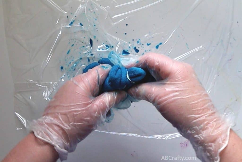 squishing a dyed blue sock while wearing rubber gloves