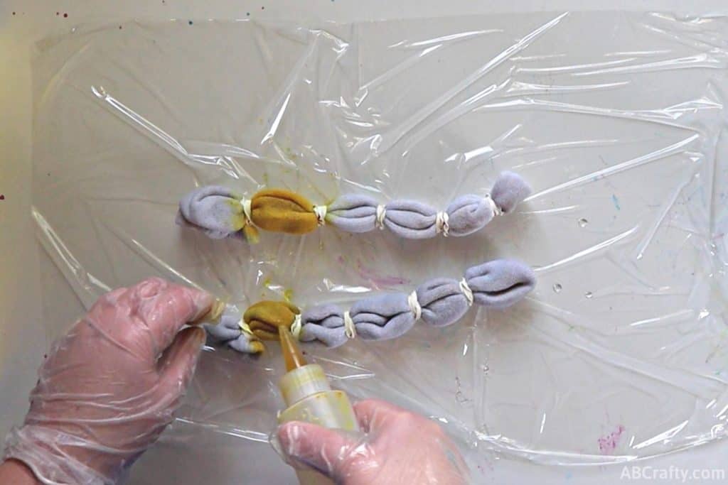 adding yellow dye to the second section of white socks wrapped in rubber bands
