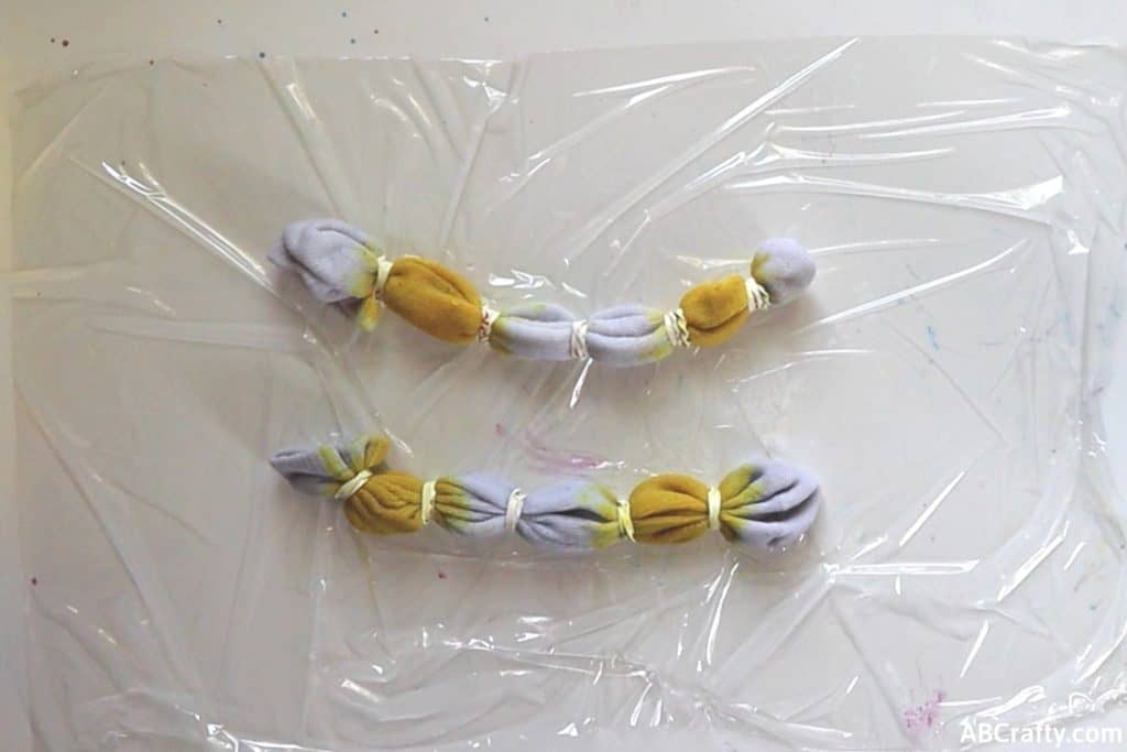 two white socks wrapped in rubber bands with two segments colored in yellow dye