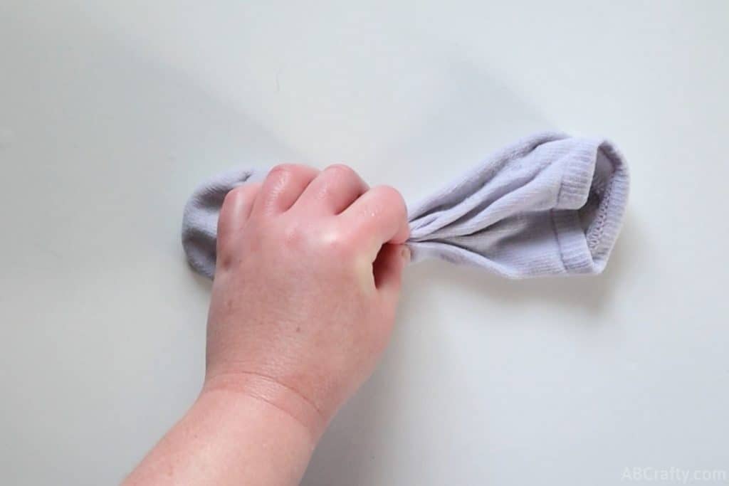 holding a white sock in the middle that has been folded repeatedly longways