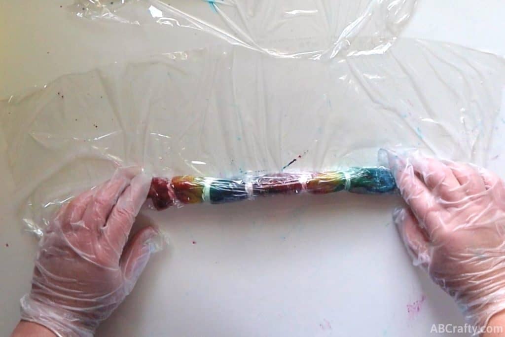 rolling a dyed rainbow tie dye sock with plastic wrap