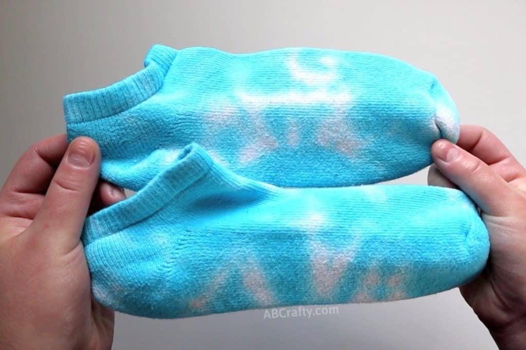 holding two blue tie dye socks