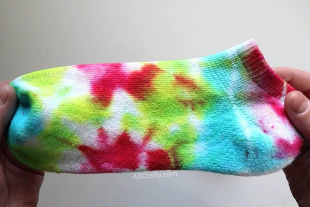 holding a multi colored tie dye sock