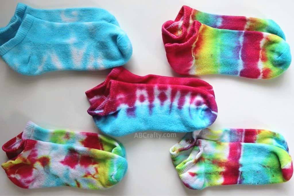 five pairs of tie dye socks in different colors, including blue, red and blue, and rainbow