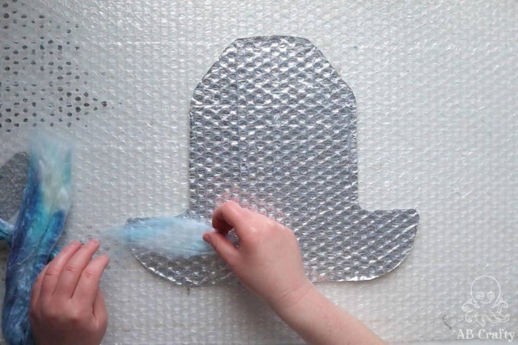 placing a thin layer of blue wool on the hat resist made of bubble wrap