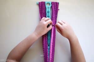tying a brown piece of yarn around a section of the pink yarn