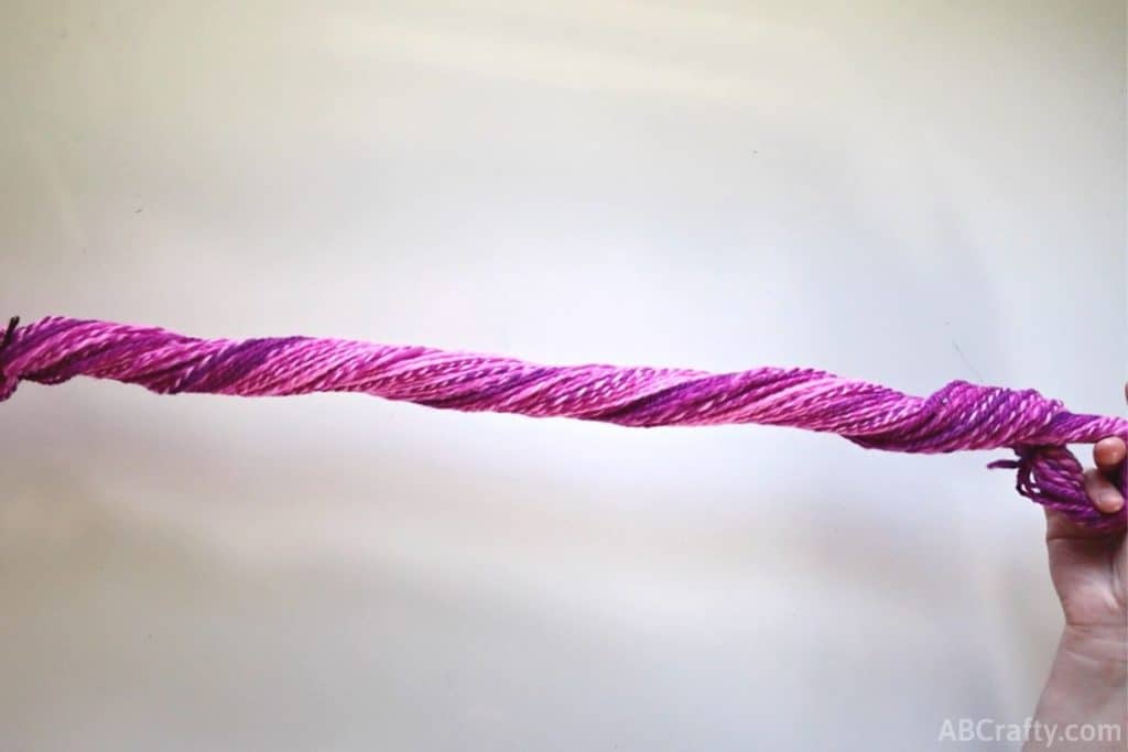 twisting a hank of pink yarn