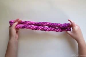 folding a twisted hank of pink yarn in half