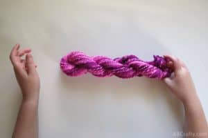 letting go of a twisted hank of pink yarn to form a twisted hank of yarn