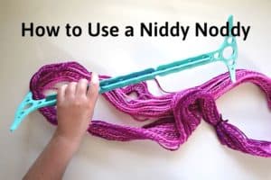 hank of hand spun pink yarn while holding a 3d printed 2 yard niddy noddy over it with the title "how to use a niddy noddy"