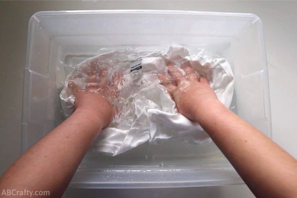 soaking a plain white t shirt in a plastic bin with water