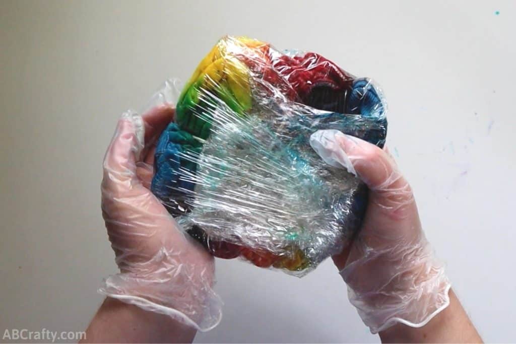 holding a tie dyed shirt wrapped in plastic wrap