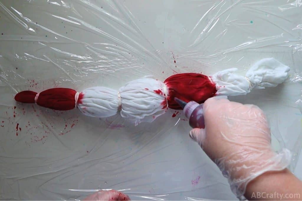squeezing red dye onto different sections of a wrapped t shirt