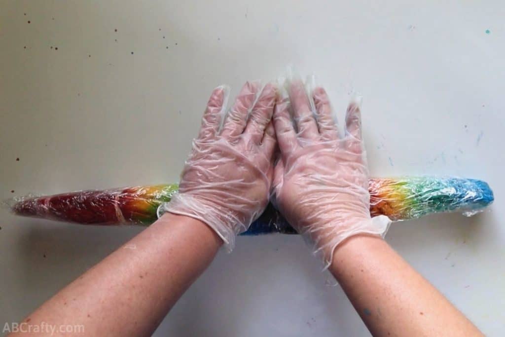 rolling a rainbow tie dye shirt wrapped in rubber bands