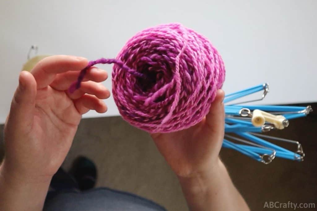 holding a newly wound up ball of pink yarn and showing the center pull of the center pull ball of yarn