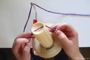 placing purple yarn into the center of a yarn ball winder