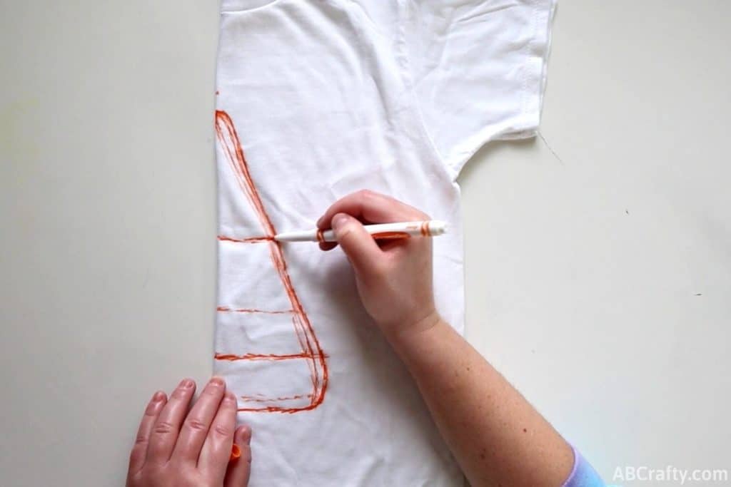 drawing half a candy corn with orange washable marker on a white cotton shirt folded in half