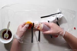 squeezing yellow dye above the orange dye at the end of a white shirt