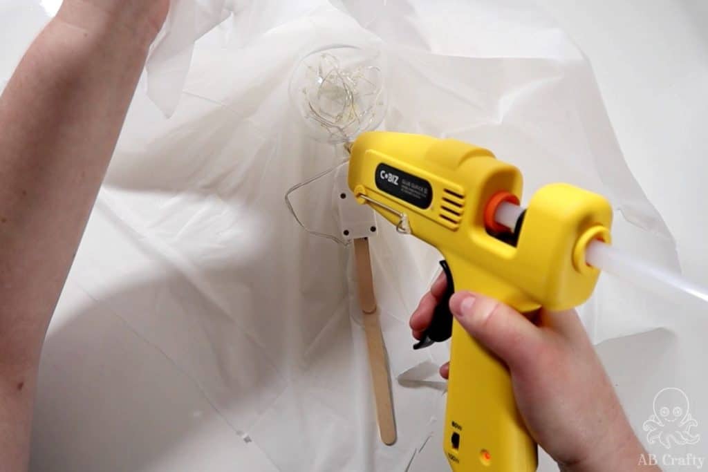 lifting the plastic table cloth to add glue to the base of the plastic ornament