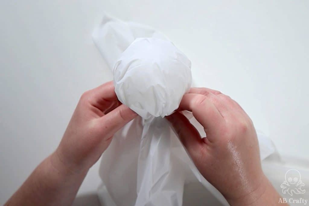 scrunching the white plastic table cloth around the plastic ornament