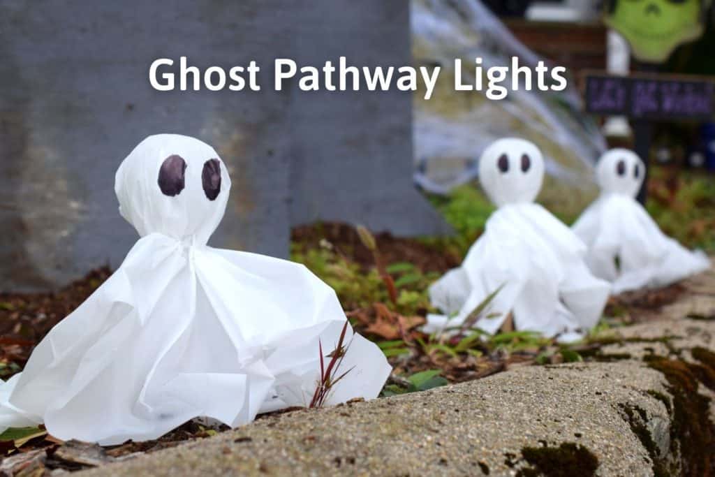diy outdoor halloween lights lining the path in front of gravestones with the title "ghost pathway lights"