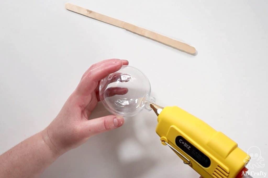 adding glue to the base of a plastic fillable ornament