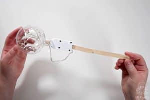 a clear plastic ornament filled with fairy lights and glued to a popsicle stick